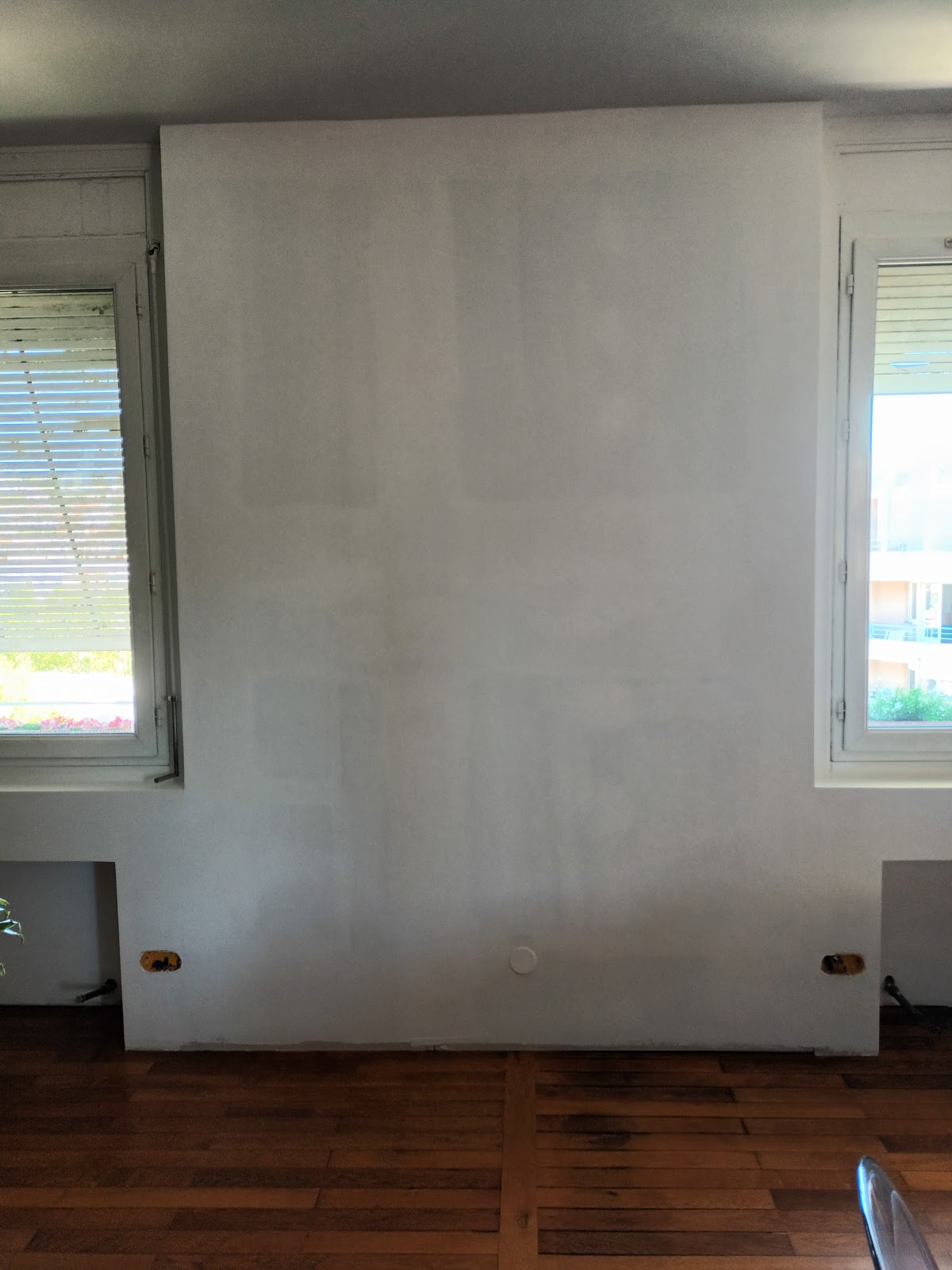 Préparation des murs d’une pièce avec deux fenêtres et un parquet
